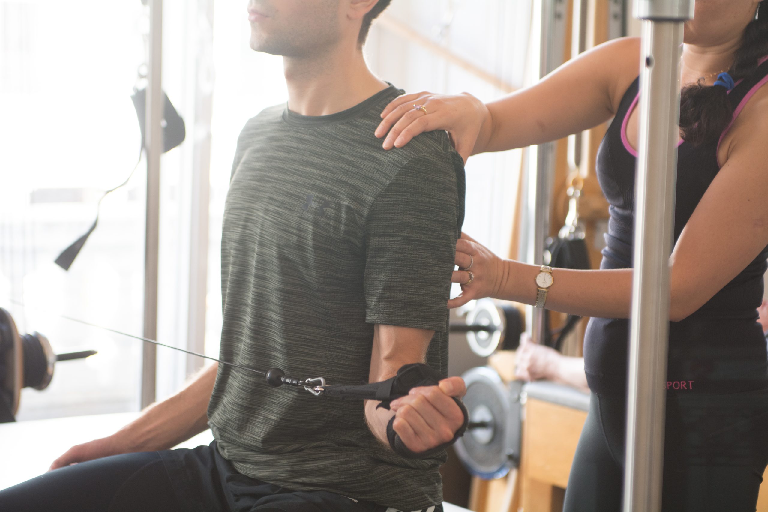 Pilates instructor assisting client with standing equipment exercise, South Kensington studio